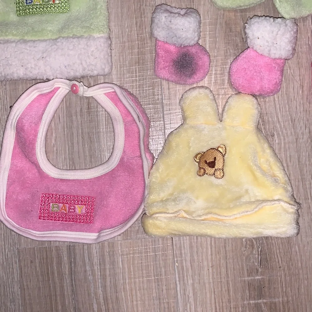 Colorful bundle of plush baby bibs, hats, and mittens